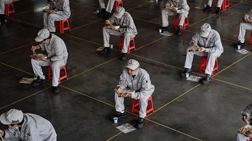 Operarios de una fábrica en Wuhan comen guardando la distancia de seguridad.