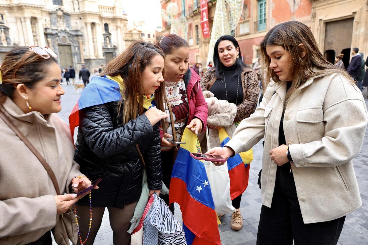 Mujeres originarias de Venezuela y residentes en Murcia siguen desde Belluga, gracias a sus móviles, las noticias que llegan de su país.