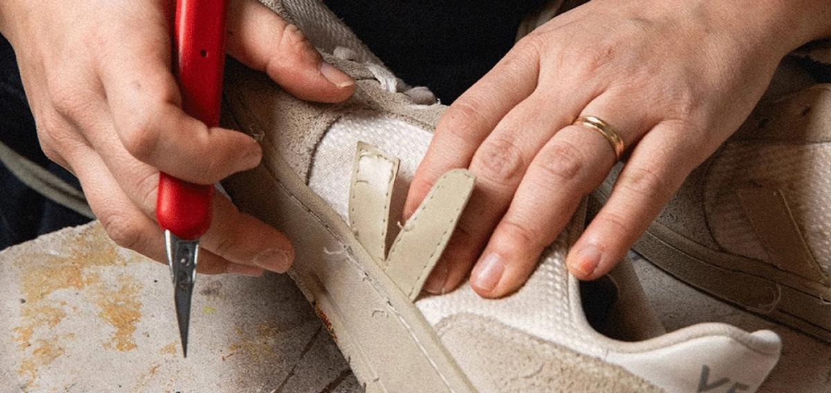 Un artesano repara una zapatilla Veja.