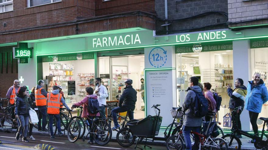 Miembros de Asturias conBici, ayer por la tarde, dialogando con Sergio Domínguez-Gil a las puertas de su farmacia en la calle Los Andes. | Marcos León