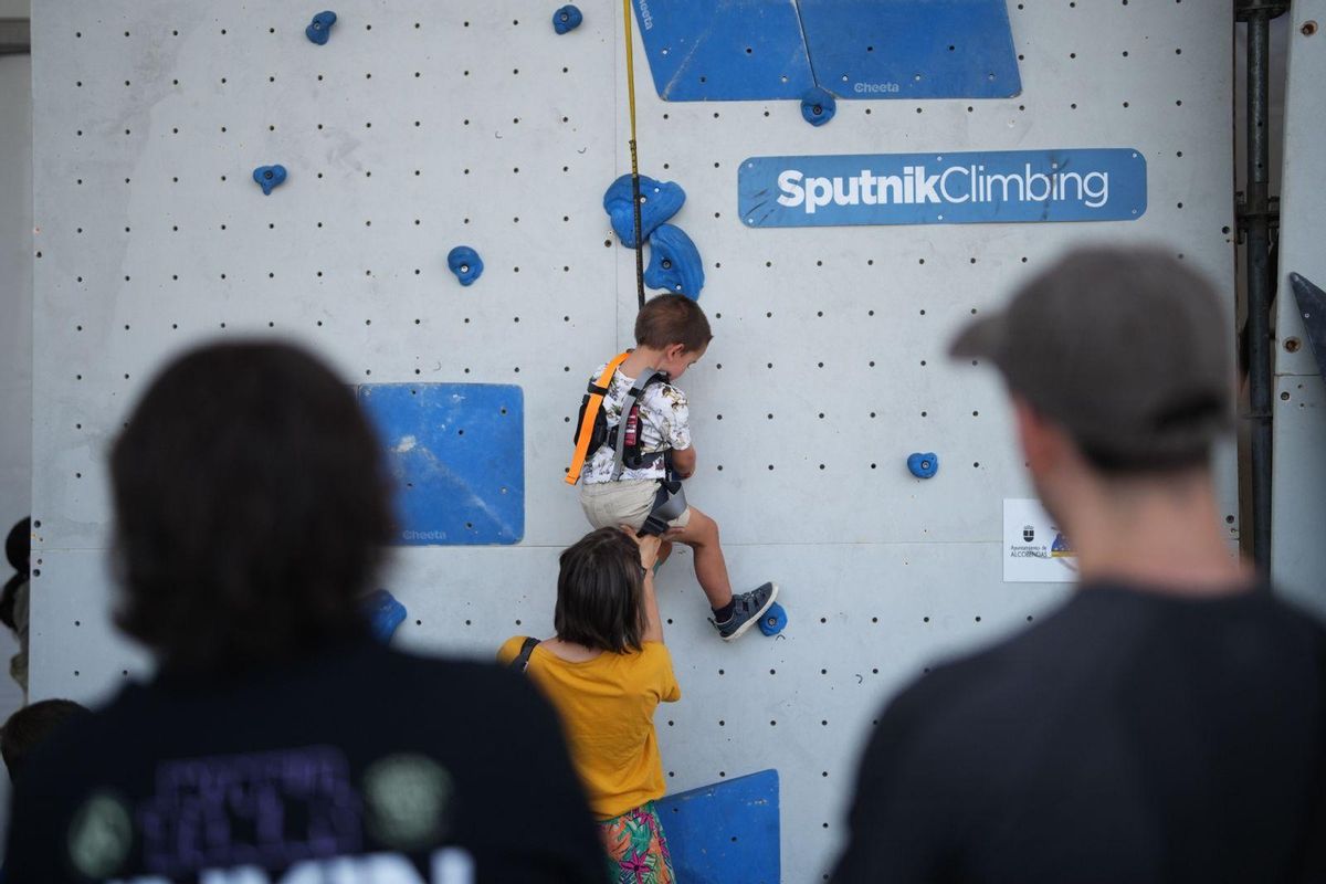 Un niño escala ayudado por su madre en el muro popular de búlder esta sábado a mediodía.