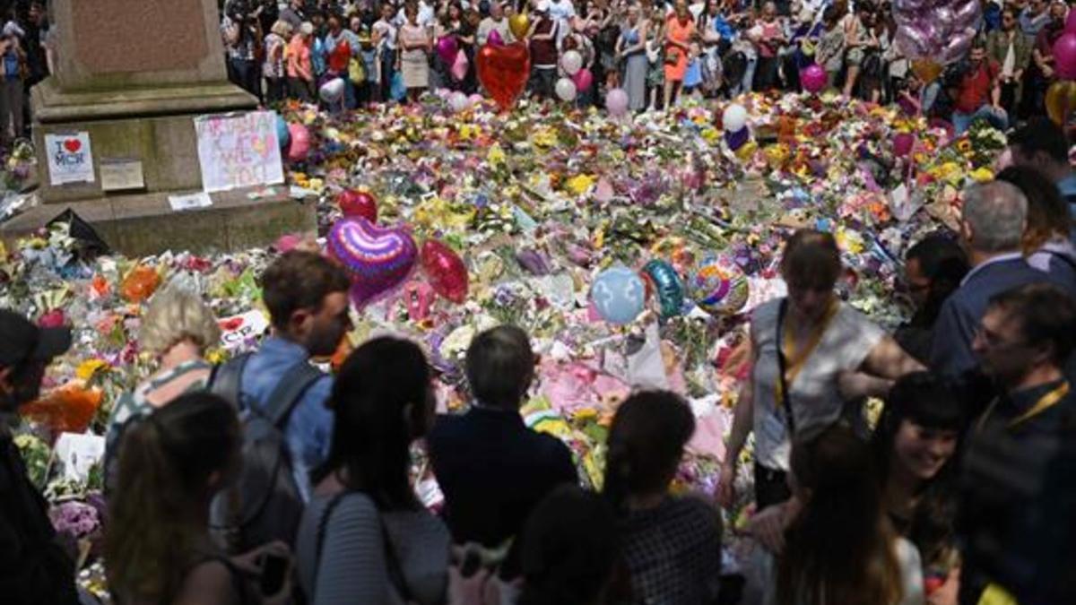 La gente se detiene y guarda un minuto de silencio ante la ofrenda floral por las víctimas del Manchester Arena en la plaza de Santa Ana de la ciudad británica.