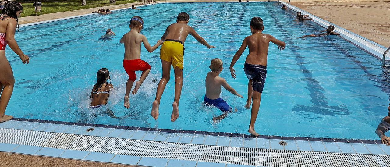 Un grupo de niños se lanza al agua en la piscina de la ciudad deportiva para hacer frente a las altas temperaturas registradas en las últimas jornadas.