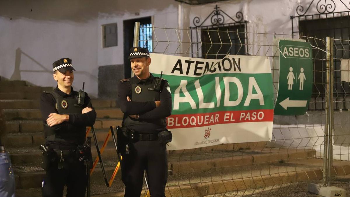 Dos policías junto a un cartel informativo de las salidas y aseos en las Cruces de Córdoba.