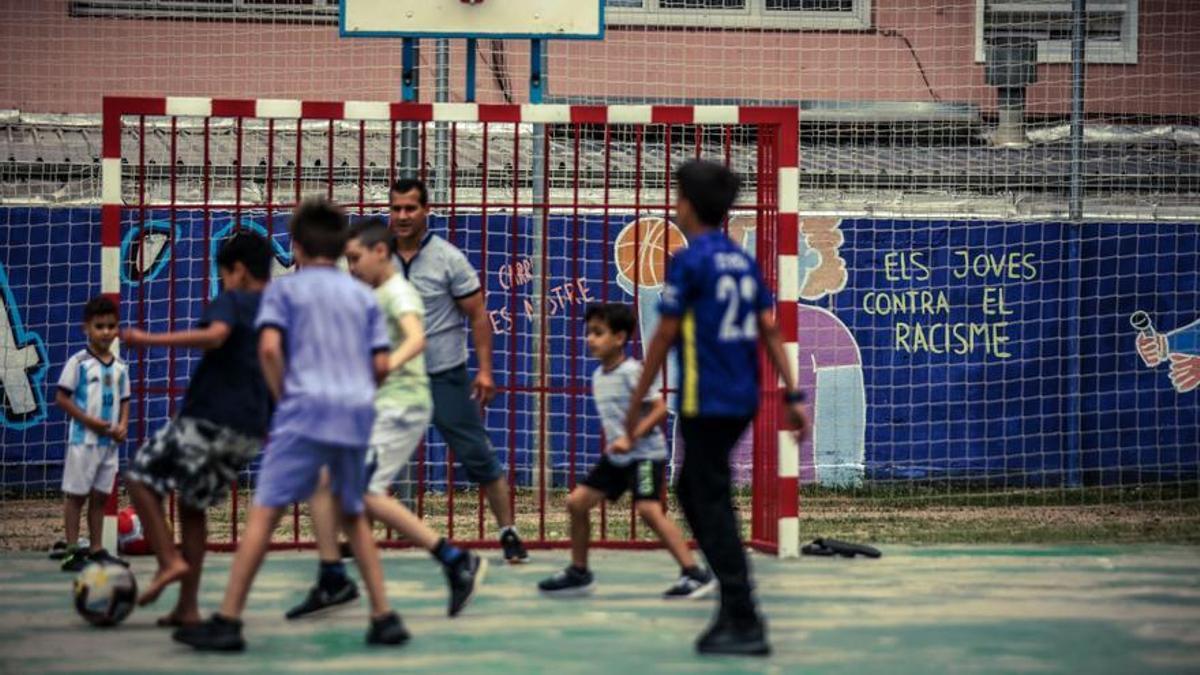 Un grupo de niños de familias de orígen migrante juegan a fútbol en una plaza de Ripoll.