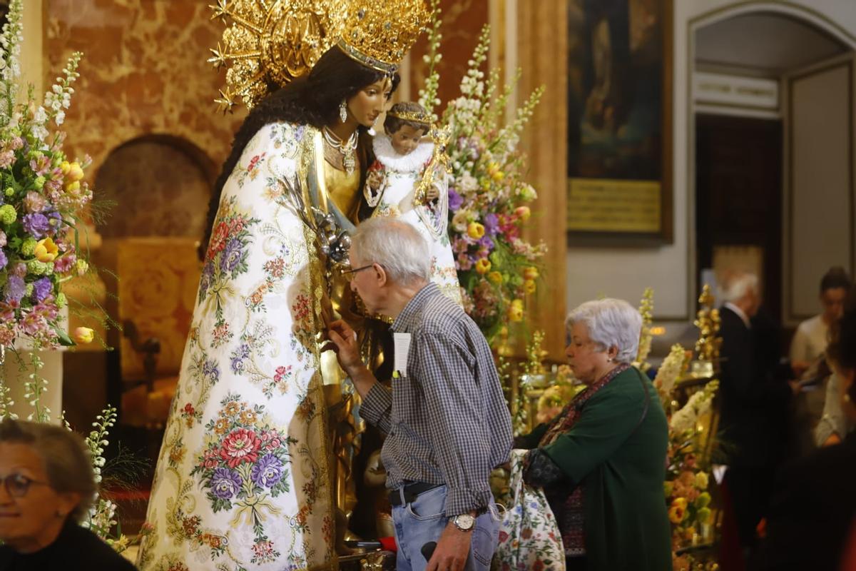 Una persona mayor besa la mano de la Virgen