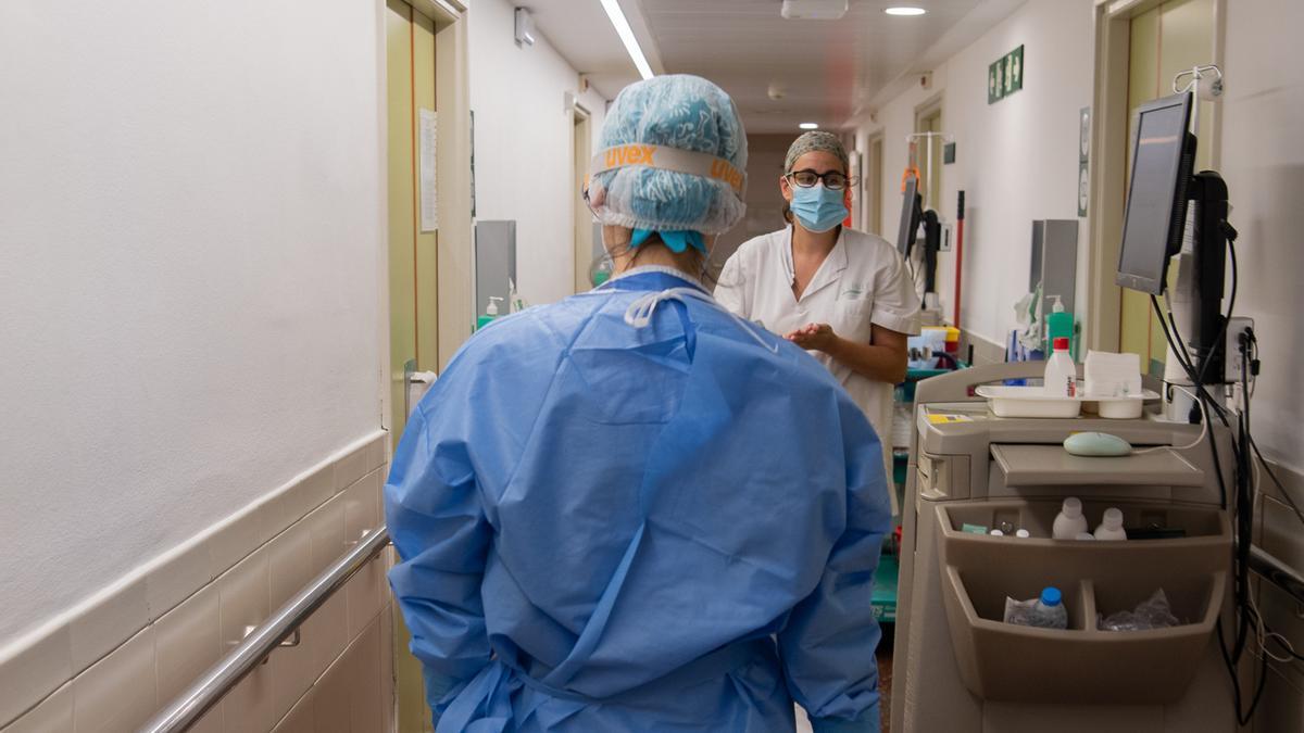 Professionals sanitaris en un passadís de la sala d'hospitalització del Servei de Malalties Infeccioses de l'Hospital Clínic, on hi ha pacients amb covid-19, en la cinquena onada de la pandèmia. Imatge facilitada el 13 de juliol del 2021. (Horitzontal)