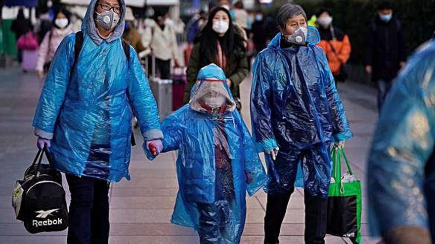Una família passeja amb la màxima protecció pels carrers de Xangai.