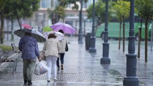 Ciudadanos paseando por la calle mientras llueve (imagen de archivo)