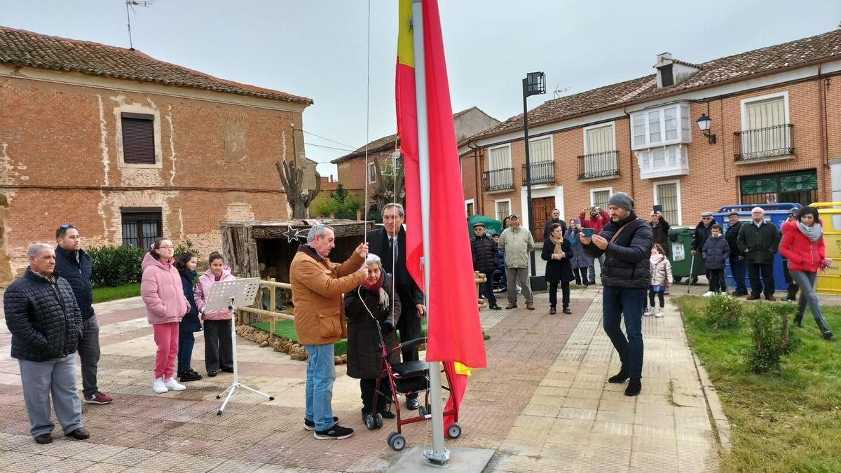 Lucía Fernández, con la ayuda de otros vecinos, iza la bandera de España