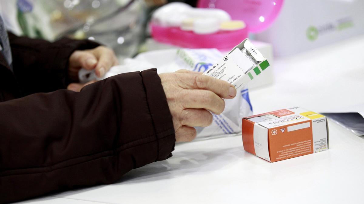 Una persona mayor retirando su medicación en una farmacia.