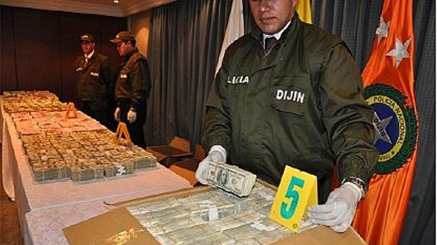 Un agente muestra una caja llena de fajos de dólares. Al fondo, los euros y más billetes estadounidenses.