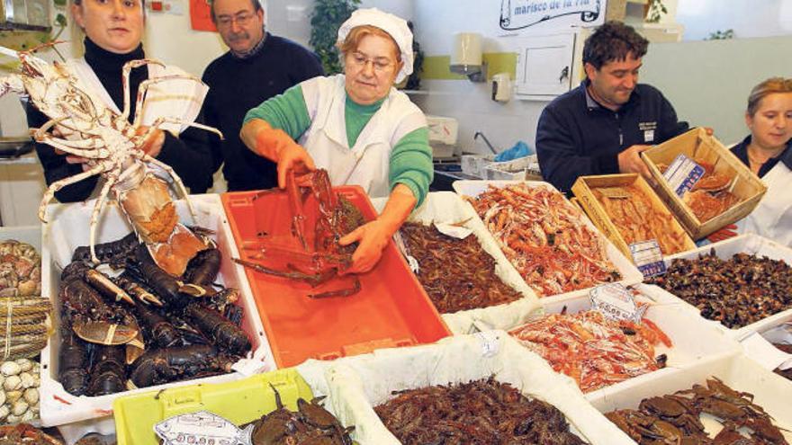Victoria González con variados mariscos en su puesto del Mercado del Berbés. // Marta G. Brea