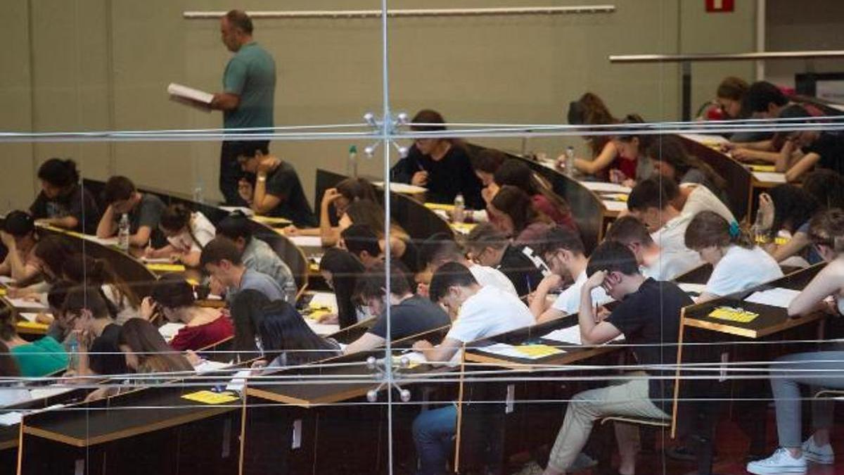 Alumnas y alumnos universitarios realizan un examen.