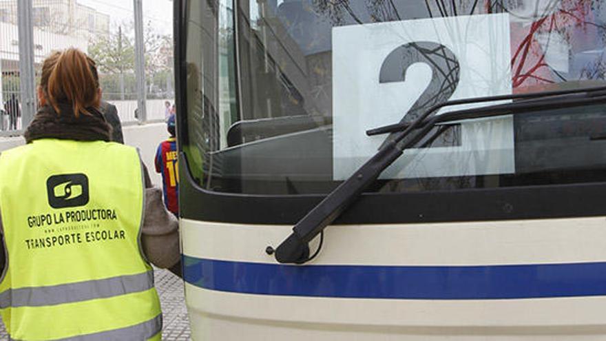 Una acompañante escolar frente a un bus que cubre el servicio.