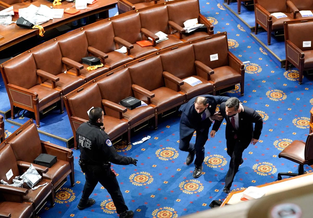 TOPSHOT - WASHINGTON, DC - JANUARY 06: Members of congress run for cover as protesters try to enter the House Chamber during a joint session of Congress on January 06, 2021 in Washington, DC. Congress held a joint session today to ratify President-elect Joe Biden’s 306-232 Electoral College win over President Donald Trump. A group of Republican senators said they would reject the Electoral College votes of several states unless Congress appointed a commission to audit the election results. Drew Angerer/Getty Images/AFP (Photo by Drew Angerer / GETTY IMAGES NORTH AMERICA / AFP)