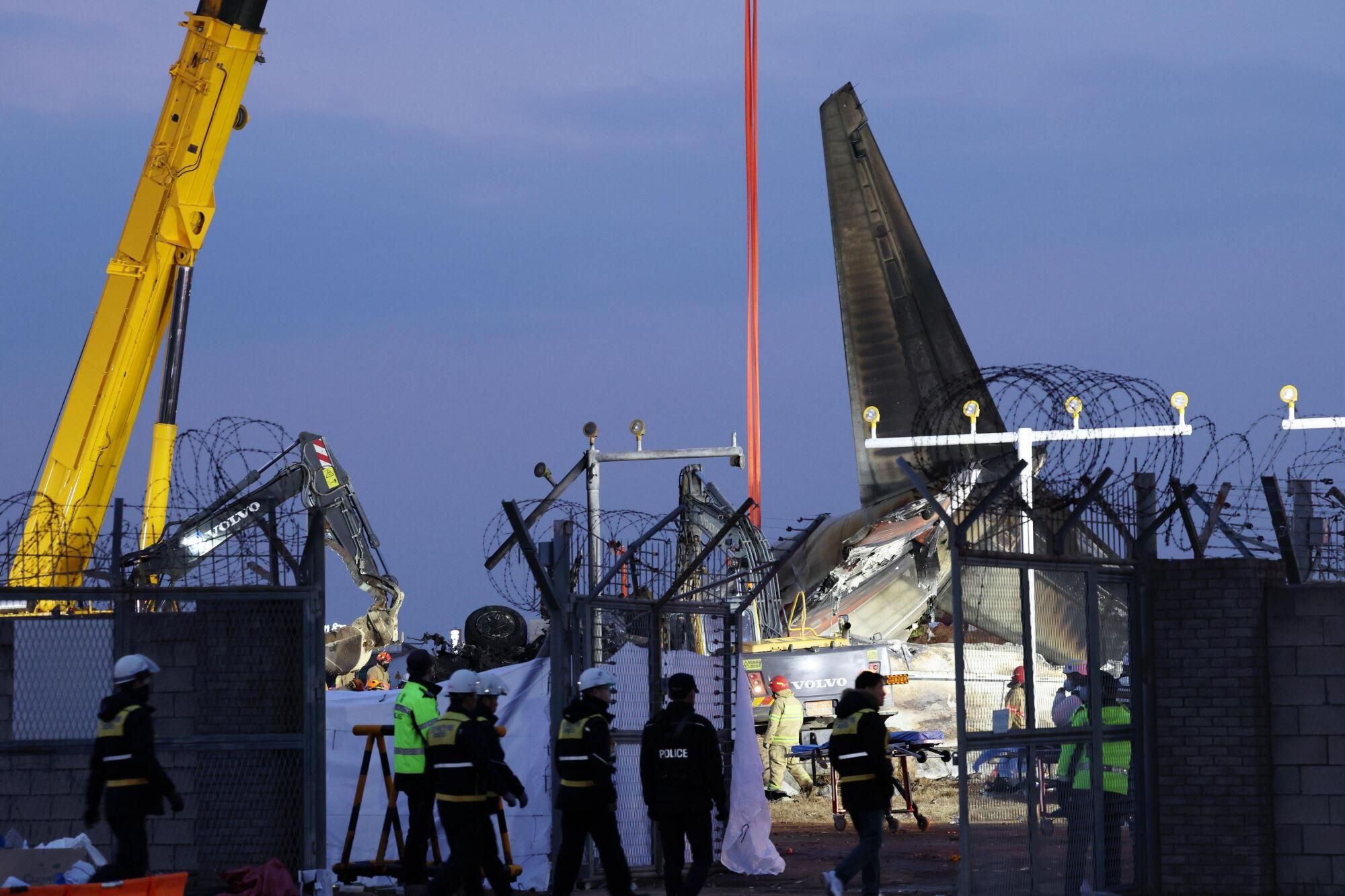 Muan (Korea, Republic Of), 29/12/2024.- A crane removes wreckage from the plane crash site at Muan International Airport in Muan, South Jeolla Province, South Korea, 29 December 2024. According to the South Korea National Fire Agency (NFA), a passenger jet carrying 181 people erupted in flames after going off the runway at an airport in South Korea's southwestern county of Muan on 29 December, leaving at least 176 people dead and 3 missing, as two crew members survived.  (Corea del Sur) EFE/EPA/YONHAP Media Only SOUTH KOREA OUT. Media Only SOUTH KOREA OUT