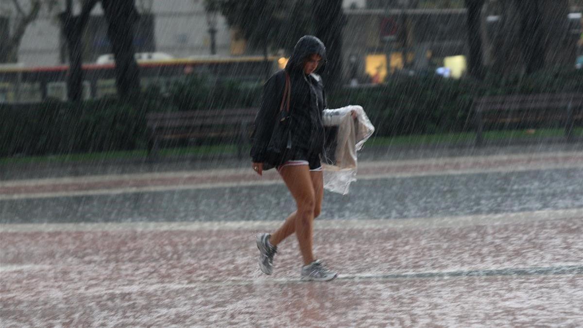 Una joven bajo la lluvia en plaza Catalunya de Barcelona, en una imagen de archivo