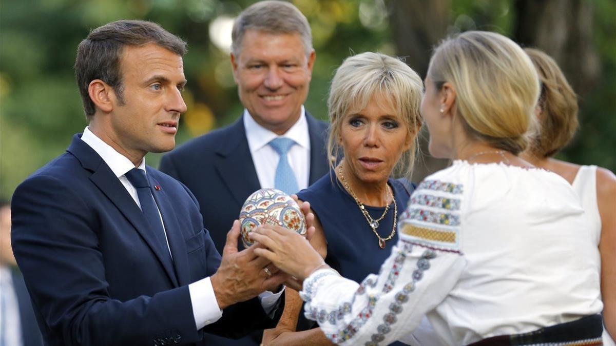 Macron (izq) y su mujer, Brigitte (centro), reciben un regalo junto al presidente rumano, Klaus Iohannis, en Bucarest, el 24 de agosto.