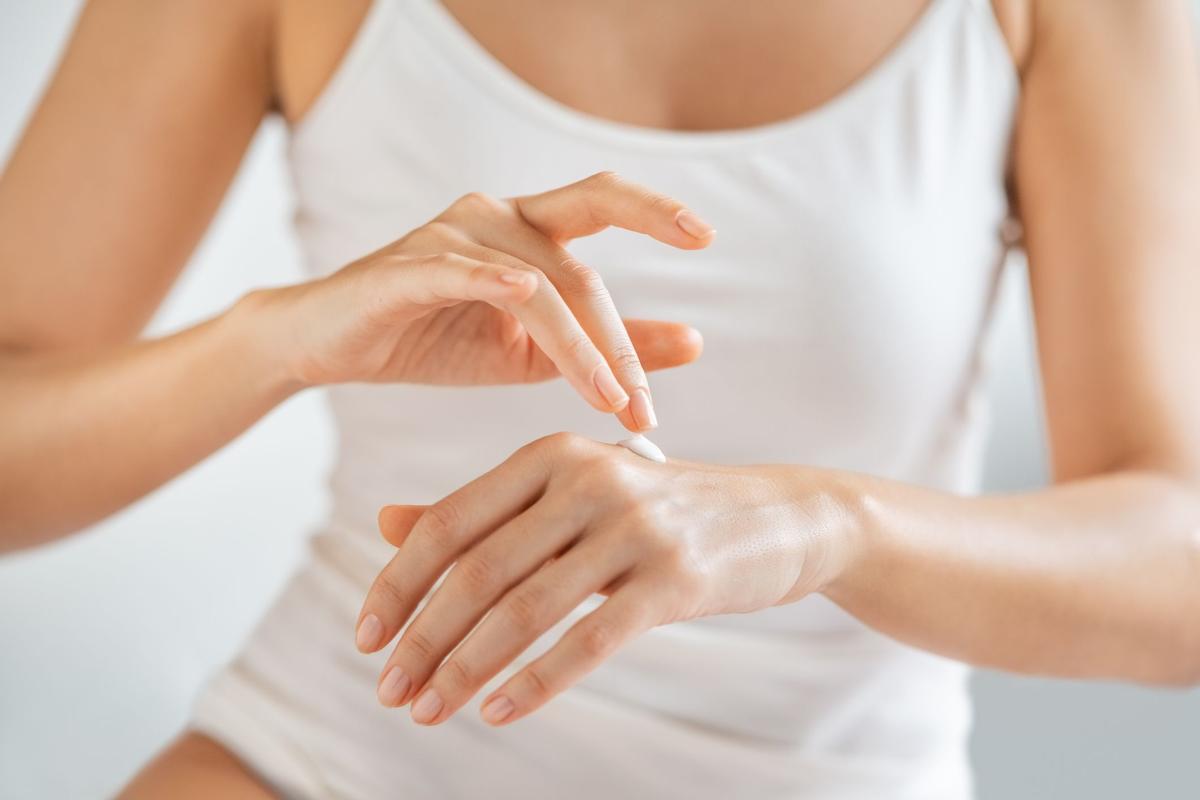 Mujer echándose crema en las manos