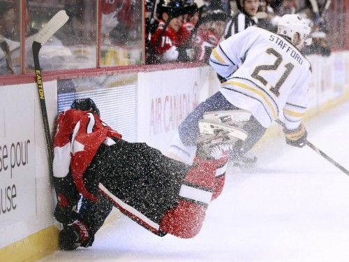 Stafford (Sabres) golpea a Regin (Senators) contra la valla durante el primer tiempo de su partido de hockey en Ottawa