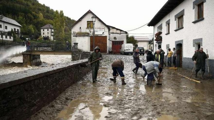 Los vecinos limpian una calle de Ochagavía, en Navarra, afectada por las inundaciones. / jesús diges / efe