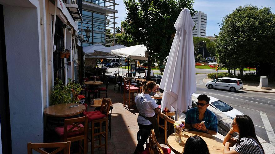 Una joven atiende a varios clientes en la terraza de La Odisea de los Vinos