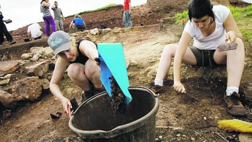 Dos colaboradoras de la campaña arqueológica en el peñón de Raíces escarban la tierra en busca de restos.