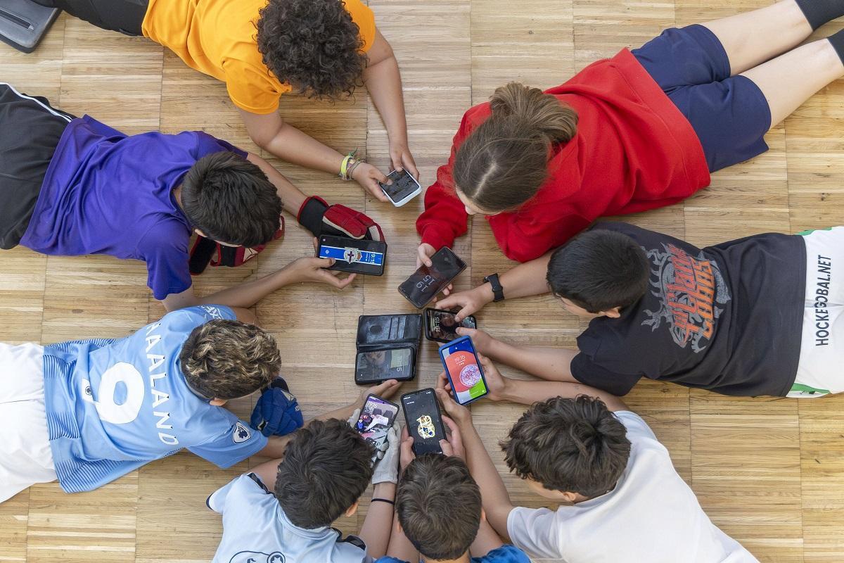 Varios niños miran  su móvil.
