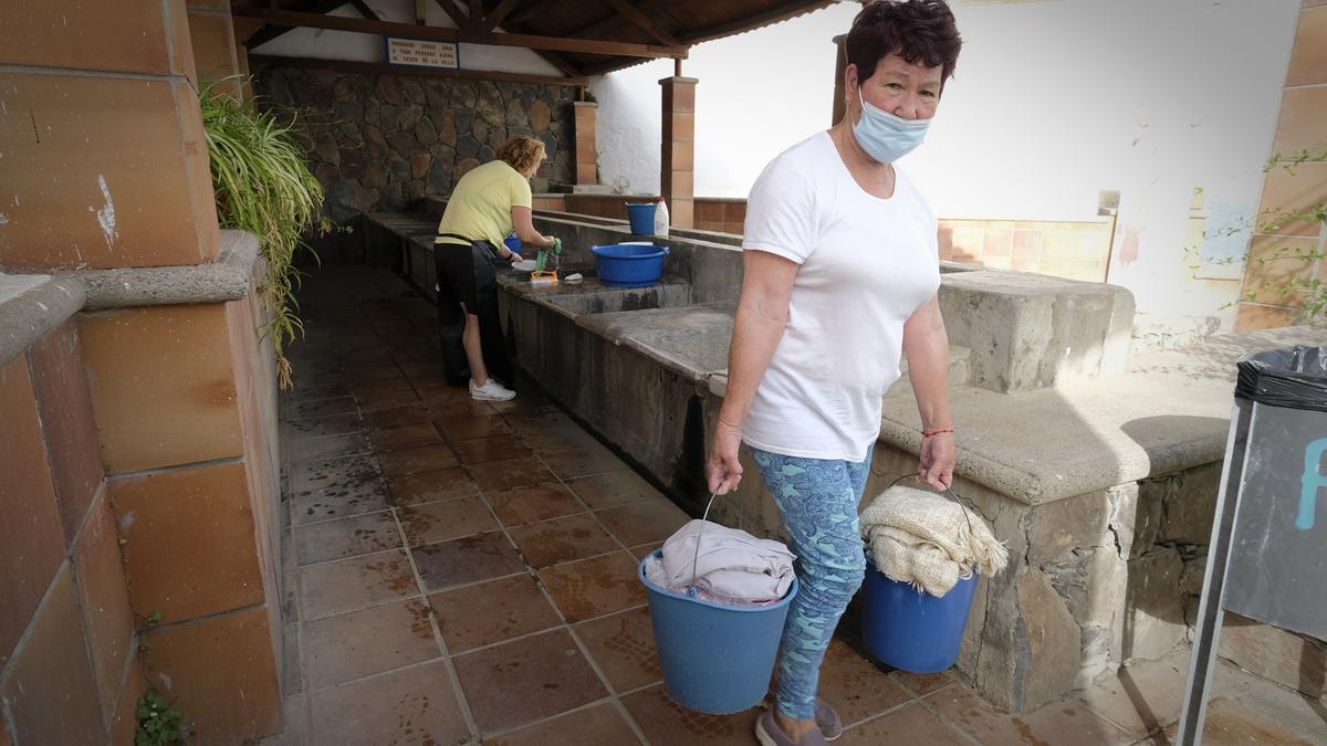 Juana cargaba son sus baldes de ropa desde el lavadero hasta su casa a pie.