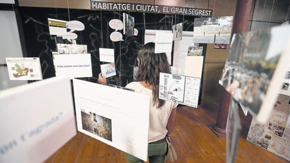 Los paneles, las maquetas y una pantalla explican los diferentes proyectos impulsados por los colectivos invitados. Una visitante consulta uno de los espacios de la exposición.