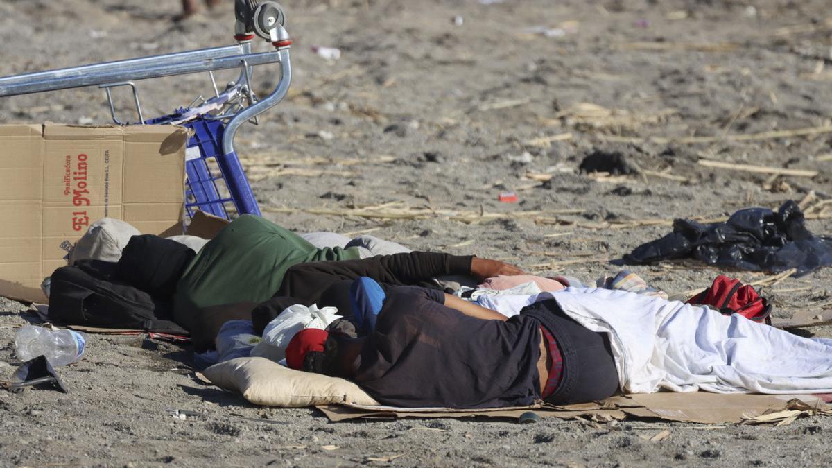 Varios migrantes duermen este sábado en la playa El Trampolín de Ceuta.