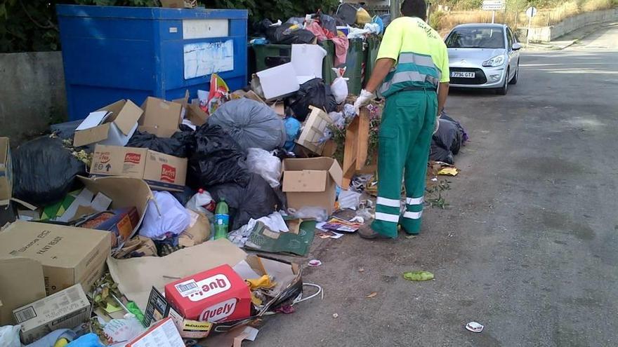Un operario recoge la basura en los atestados contenedores del camino de Santa Magdalena.
