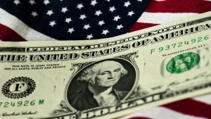 Un billete de un dólar por encima de una bandera de Estados Unidos.