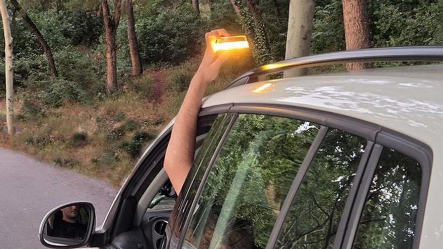 Un conductor activa una balisa V-16 des de l’interior del vehicle.  | EL PERIÓDICO