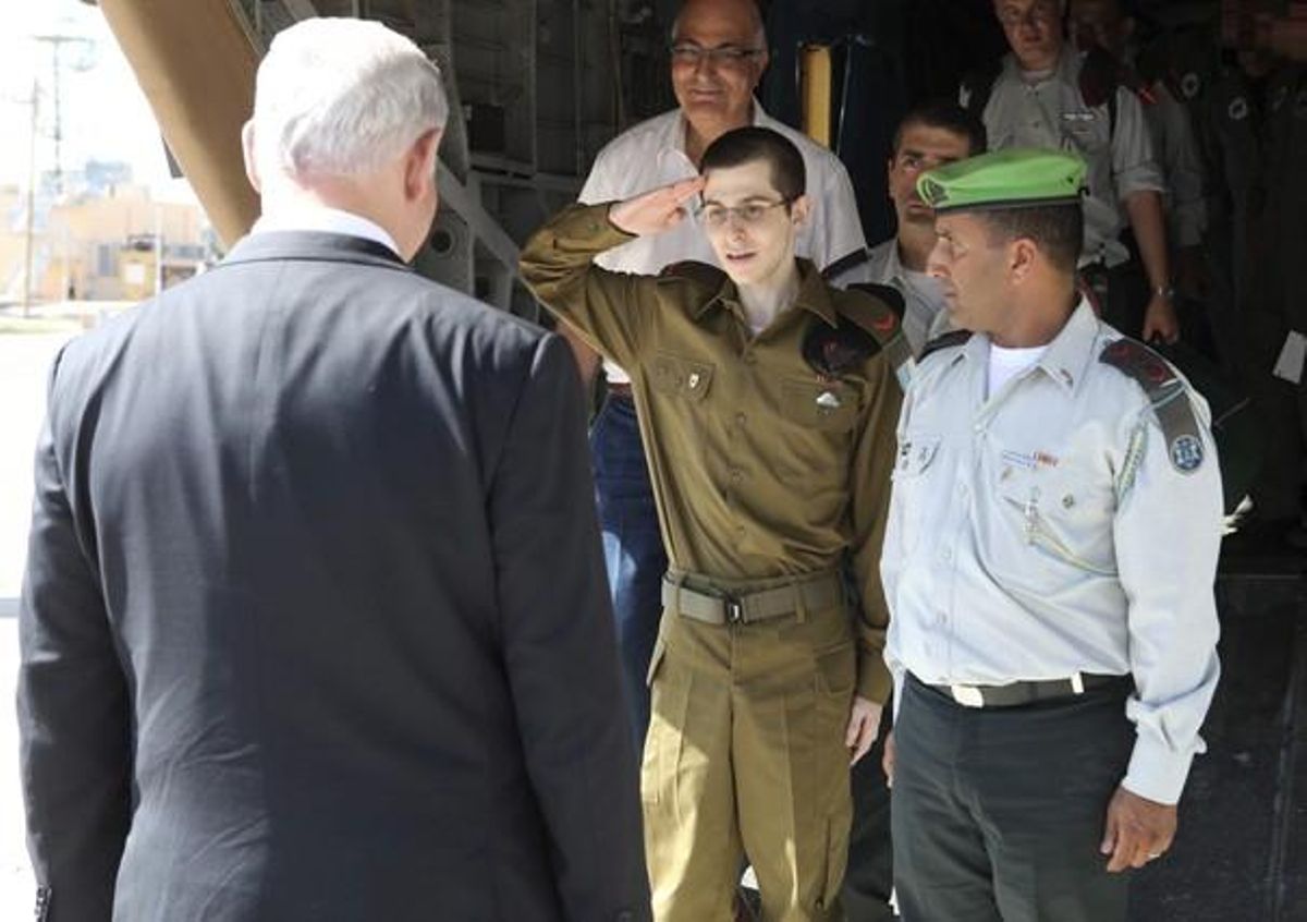 El soldat israelià alliberat Gilad Shalit (al centre i de verd) saluda el primer ministre israelià Benjamin Netanyahu (d’esquena) a l’arribar a la Base Aèria de Tel Nof, Israel.