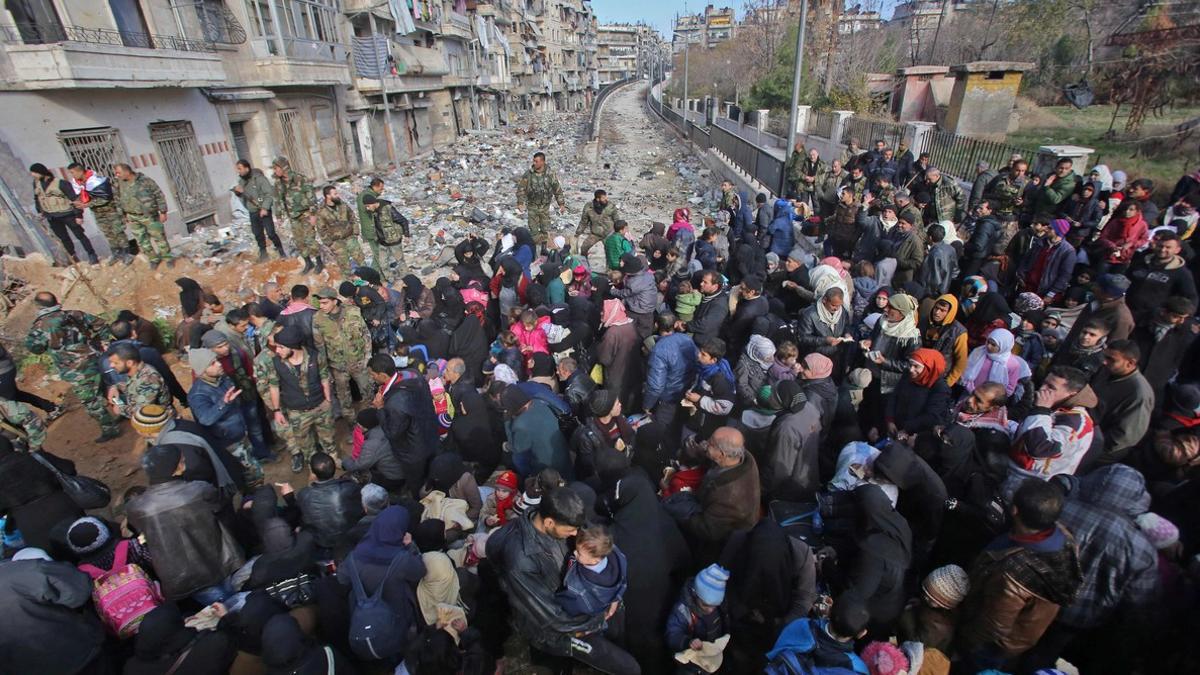 Decenas de civiles esperan en un control del Gobierno sirio a ser evacuados de las zonas rebeldes de Alepo, el jueves.