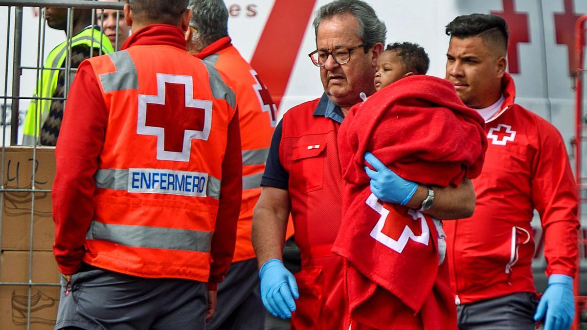 Voluntarios de la Cruz Roja atienden a un menor que llegó en patera al muelle de Arguineguín.   | | JUAN CARLOS CASTRO