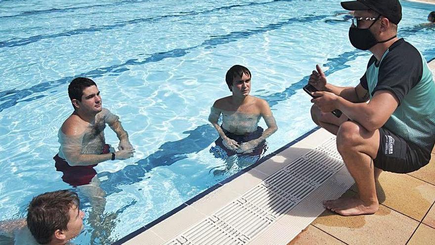 Un socorrista informant tres banyistes sobre les normes de la piscina