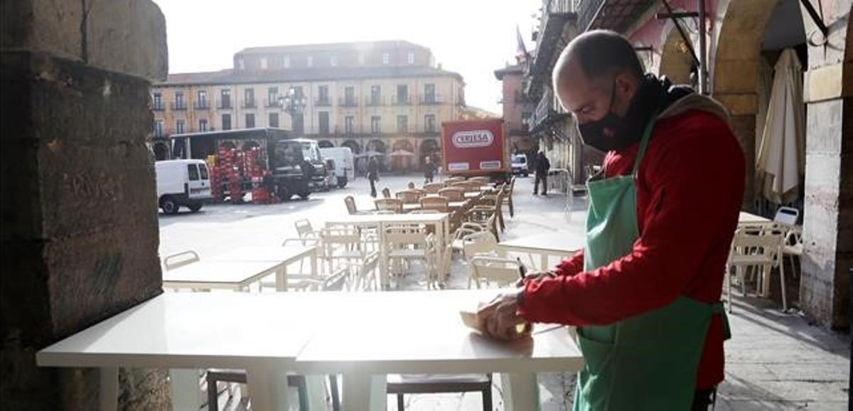 Un camarero prepara la terraza de un pequeño bar.