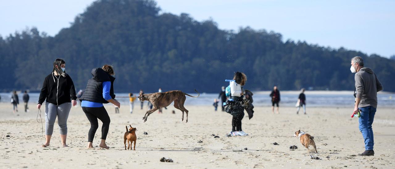 Un grupo de personas disfrutan del buen tiempo en la playa de Lourido, en Poio