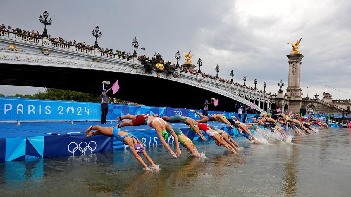 Las participantes saltan al río Sena durante la salida de la prueba de triatlón femenina desde el puente de Alejandro III en Paris