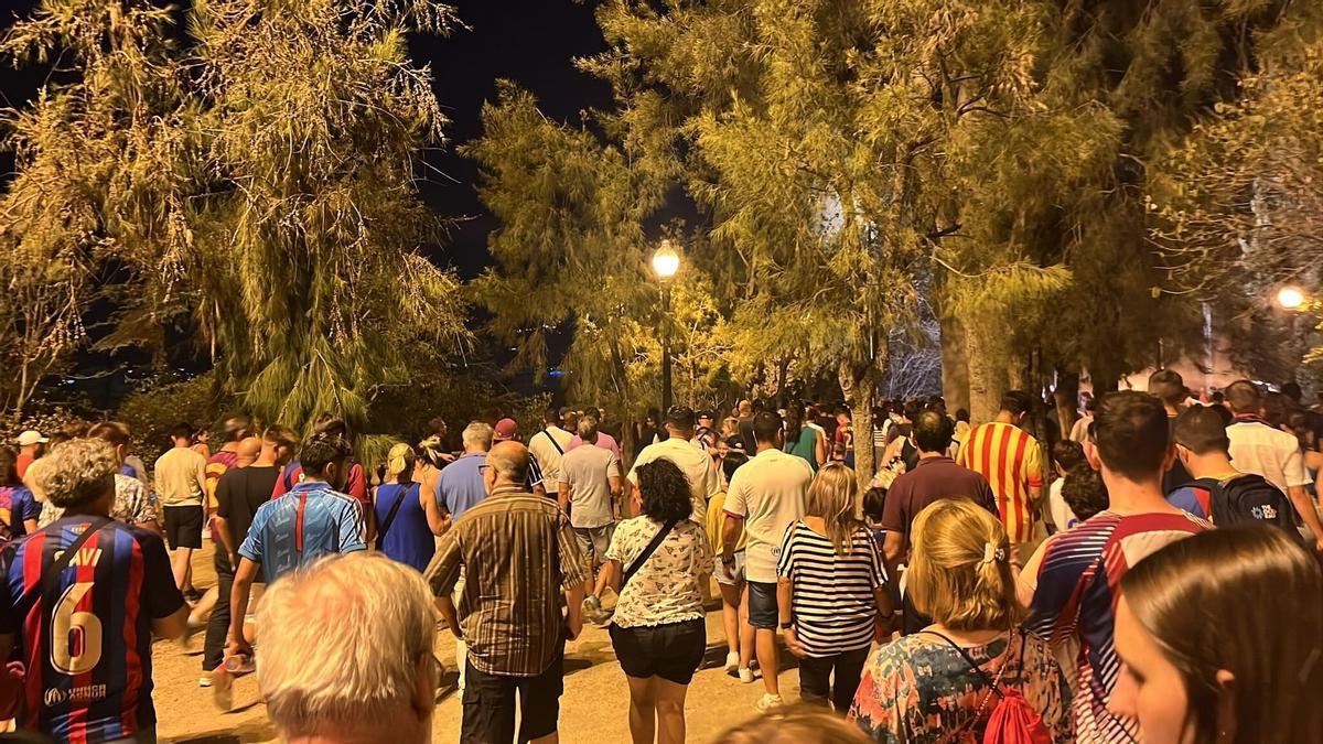 Aficionados bajan, tras el final del partido, por el parque de Montjuïc.