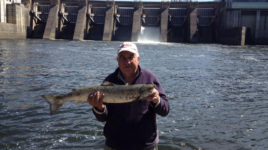 Salvador Ortega mostrando el salmón junto al embalse de Frieira, donde lo capturó.