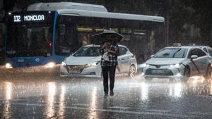 Una persona cruza la calle bajo la lluvia, a 29 de mayo de 2023, en Madrid (España).