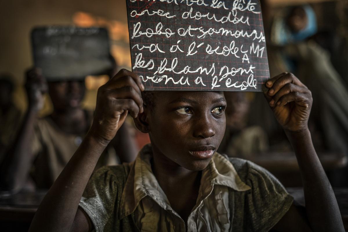 ’Aulas peligrosas. Enseñar el Corán o morir’. Un niño muestra una pizarra con ejercicios que les ha pedido el profesor en una escuela cerca de la frontera de Burkina.