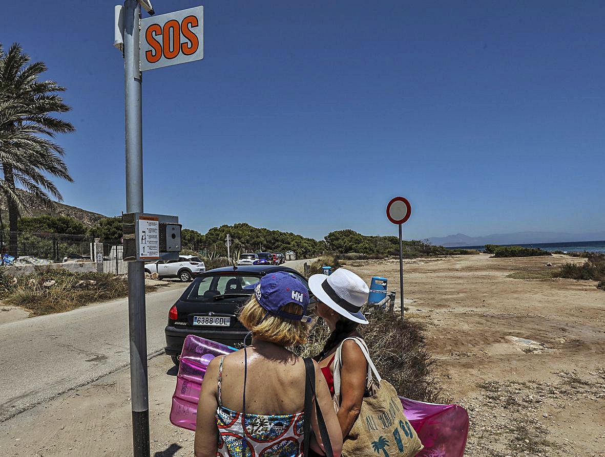 A la izquierda el panel SOS que se ha instalado para pedir auxilio y a la derecha un socorrista vigilando una de las calas de Santa Pola esta semana.  | ANTONIO AMORÓS