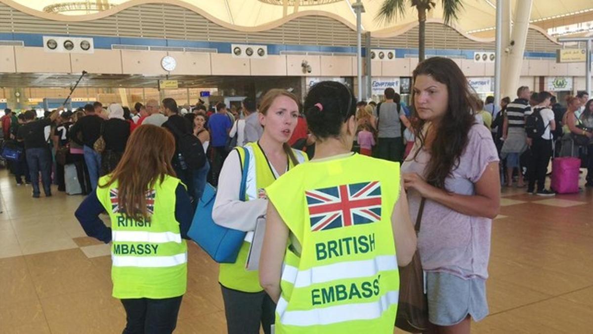 Una turista habla con personal de la Embajada británica en Egipto mientras otros hacen cola para el 'check in', en el aeropuerto de Sharm al Sheij, este viernes.