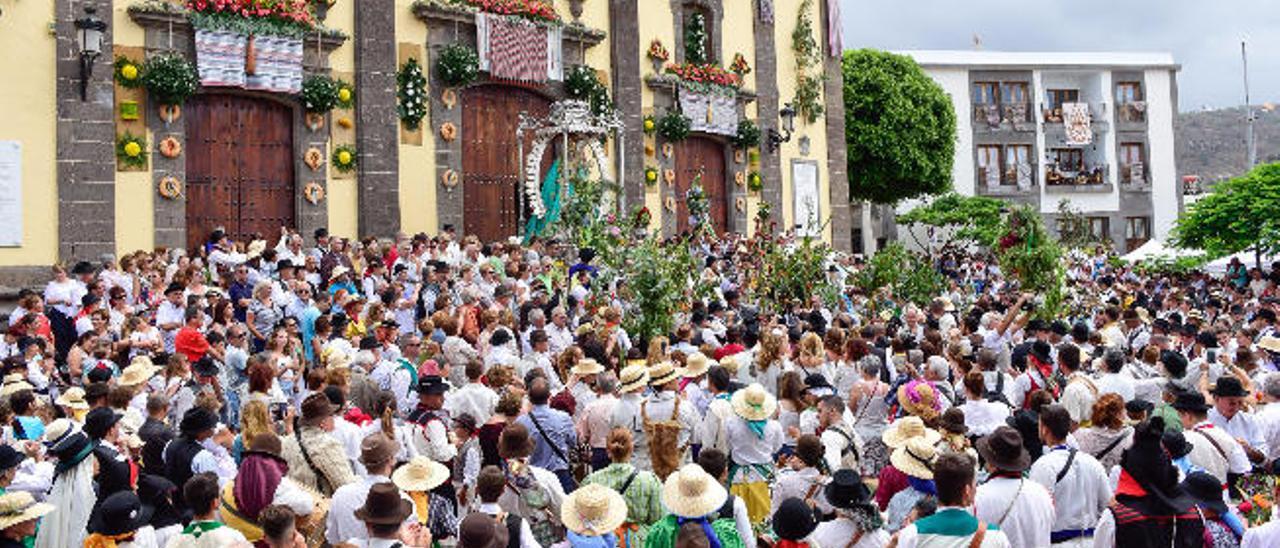 A la izquierda, el numeroso público observa a la Virgen en la entrada de la iglesia. A la derecha, varios participantes en la comitiva hacen sonar sus caracolas.