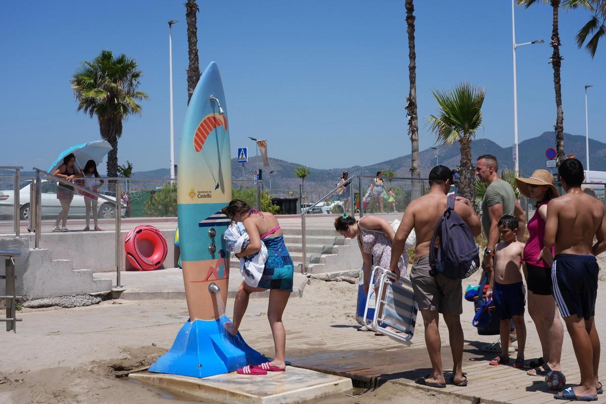 Veraneantes en Castelló junto a una de las duchas de la playa del Gurugú.